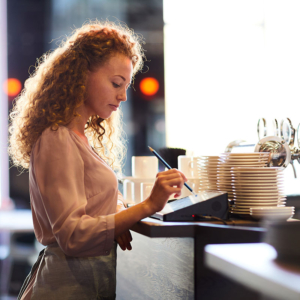 Pensive waitress adding order in restaurant POS